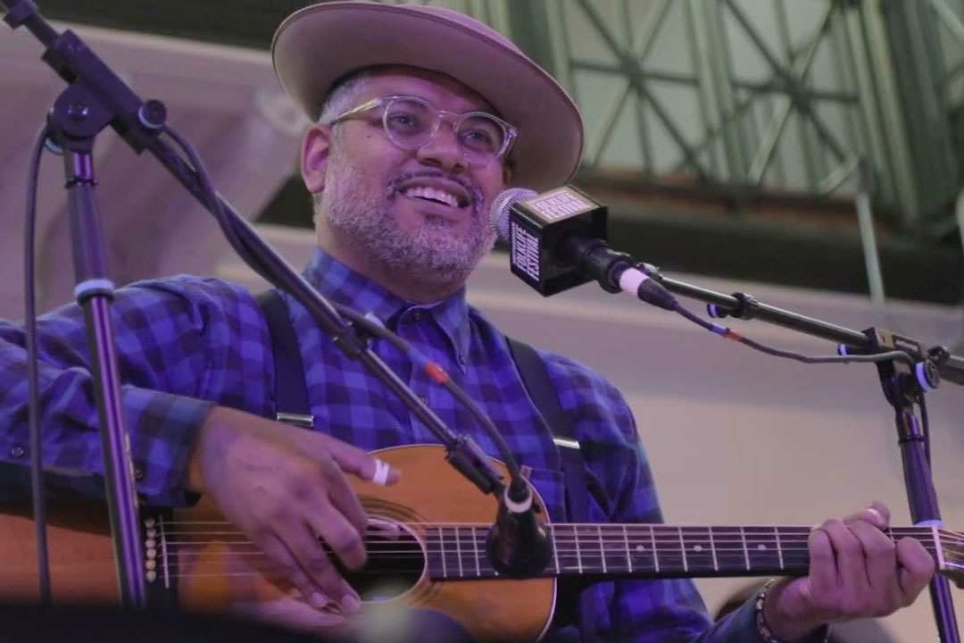 A man plays acoustic guitar and sings on stage.