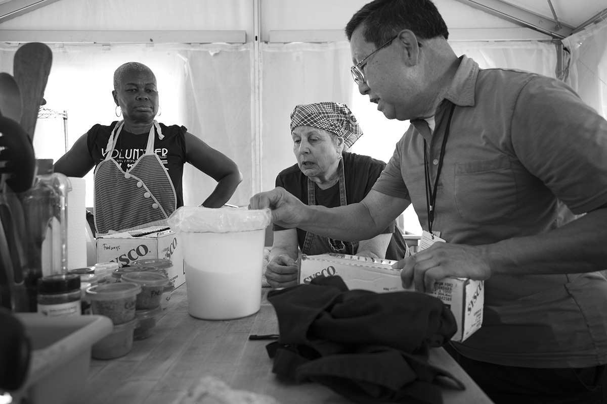 Black-and-white photo of three people working in the backstage kitchen.