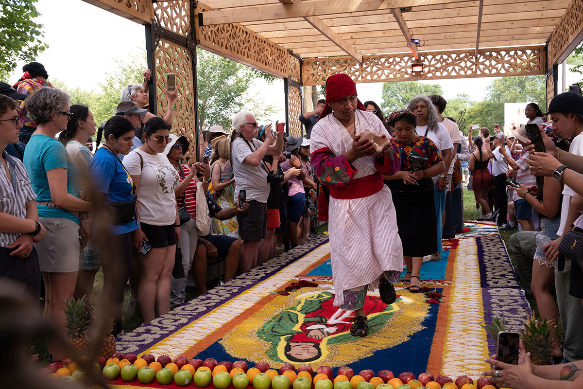 Ubaldo Sánchez leads the way on the closing ceremony of the second alfombra, followed behind by his fellow artist Rocsana Sánchez, Rosanna Esparza Ahrens and Ofelia Esparza from the Ofrenda tent, Program Assistant Vicky Mogollón-Montagne, Intern Luis Guevara-Flores, and the Mariachi Aztlán.