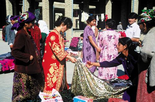 Women inspect cloth in this bazaar in Bukhara, Uzbekistan. Local as well as foreign cotton and silk fabrics continue to be traded in the markets of most Central Asian towns.