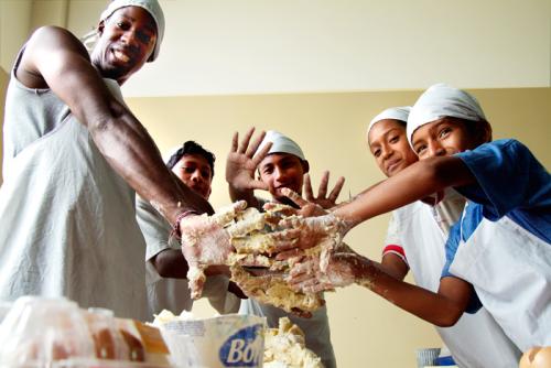 Peace Corps volunteer Kadeon Thomas learns how to bake bread as part of a project designed to help children in Ecuador earn additional money for their families.