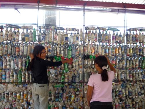 Two Guatemalan students stuff plastic bags into the spaces between plastic bottles.