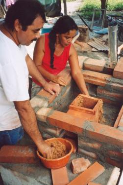In Tiquisate, Guatemala, Leonel Jarqu&iacute;n (left) and Sagrario Cardona use a mud mixture to seal the combustion chamber of a fuel-efficient cookstove where the flames and heat concentrate.