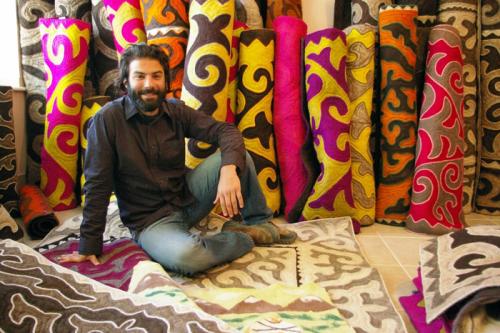 Peace Corps volunteer David Stewart poses among a beautiful display of shyrdak, or ornate felt rugs.