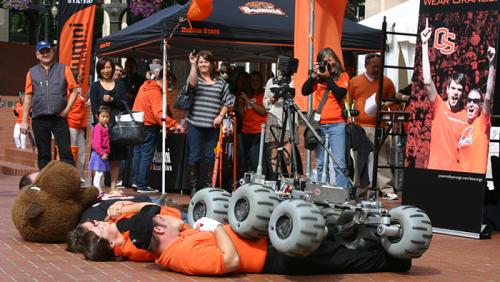 Oregon State University students guide a robot over the university mascot and other volunteers.district.