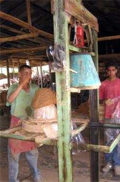 Workers use a hydraulic jack to mold ceramic filters in the Dominican Republic workshop.