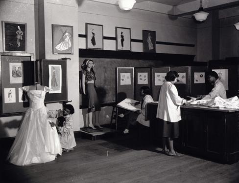 Before the end of segregation, vocational schools like the Margaret Murray Washington Vocational School taught young women students the business of fashion design. This photograph illustrates skills taught at the school: draping a dress on a mannequin, sk