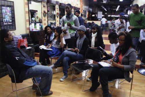 Participants in the Dr. Beverly J. Robinson Community Folk Culture Internship Program at Mind-Builders Creative Arts Center in the Bronx, New York, interview master barber Dennis Mitchell about his two decades of experience.