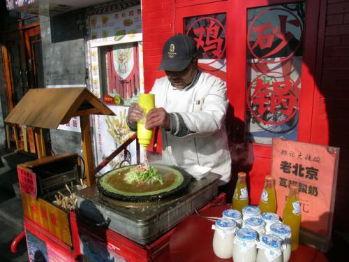 A vendor prepares a popular street food, jian bing, in Beijing, 2014.