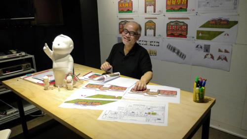 Danny Yung with the plans for the Tian Tian Xiang Shang Gateway at the Zuni Icosahedron studio in Hong Kong, 2014.