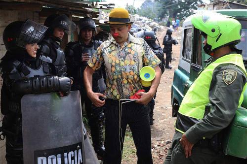 A Clowns Without Borders artist performs for riot police preparing to raze a settlement in Colombia.