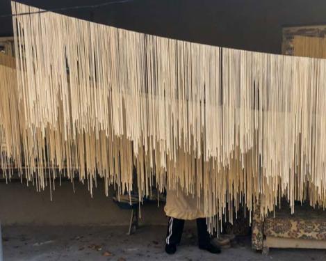 Women prepare arishta, a hand-pulled pasta, and hang the long noodles on a line to dry.