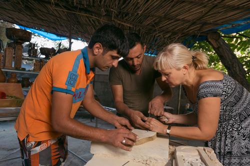 The Ghazaryans demonstrate carving for tourists on their way to visit Noravank monastery. Some of the most curious tourists also try their hand at carving.