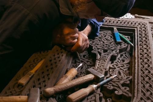 Hovhannisyan works on the detail of a khachkar made of black tuff stone.