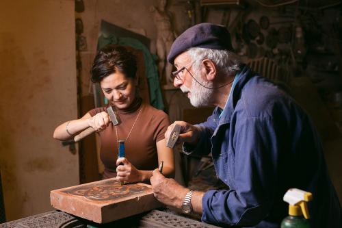 Hovhannisyan supervises as apprentice Gayane Manucharyan carves a piece of red tuff stone. 