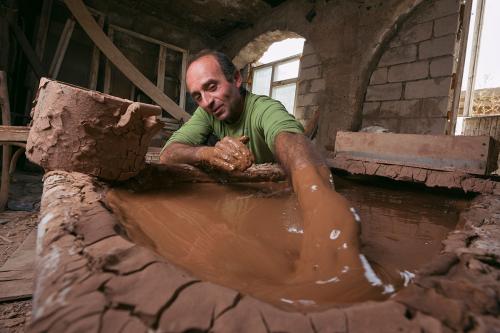 Potter Vahagn Hambardzumyan mixes clay after digging it from the hillsides outside his workshop in Sisian.