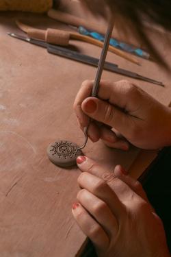 Gasparyan adds detail to a clay pendant.