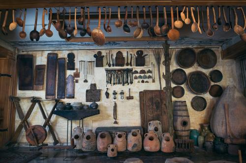 A display in the Museum of Woodcarving features a range of handmade objects from a traditional Armenian home, including carved spoons and large clay salt jars.
