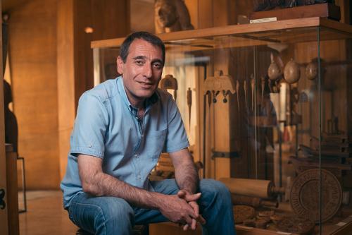 Woodcarver Vahagn Amiryan inside the Museum of Woodcarving, near a case with objects he carved for the museum.