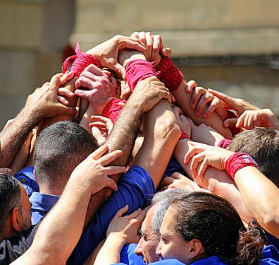 Castellers build the pinya (base) of a human tower, which acts as a safety net for the people on the upper levels. 