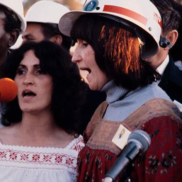 Woman singing in a hard hat.
