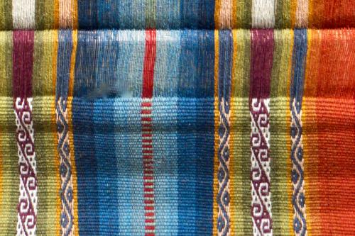 Closeup of a colorful woven textile with stripes and wavey pattern.