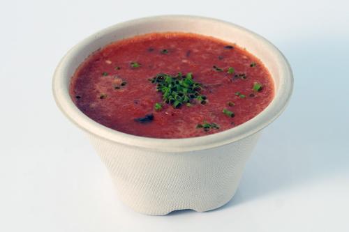 Cup of red soup with green chive garnish.