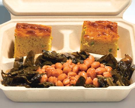 Sauteed greens and tan beans with two pieces of yellow cornbread in a cardboard container.