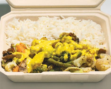 Green and orange vegetables with yellow sauce and white rice in a cardboard container.