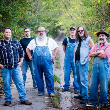 Six men in denim jeans and overalls.
