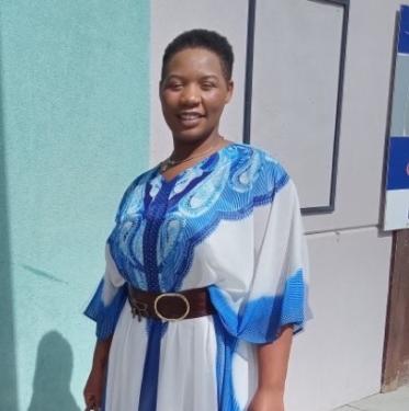 A woman in a blue and white dress stands.