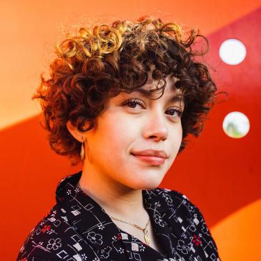 Pura Coco in front of striped orange background.