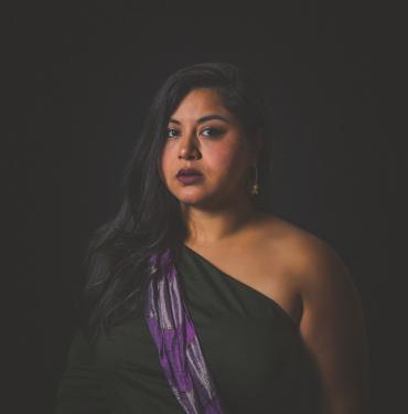 A woman in a black dress and purple sash.