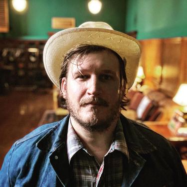 Willi Carlisle in straw cowboy hat and denim jacket.