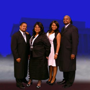 Four men and women pose against blue backdrop.