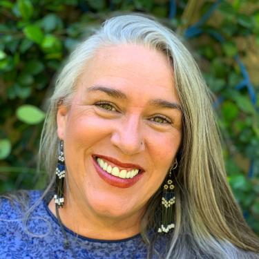 Close-up of a smiling woman with beaded earrings.