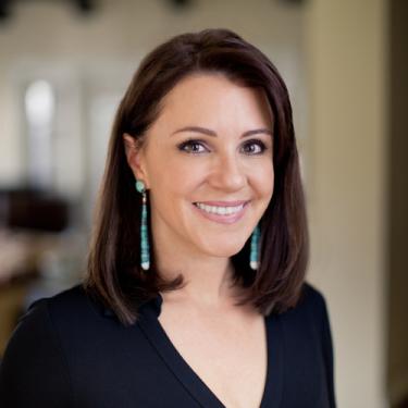 A smiling woman with blue earrings.