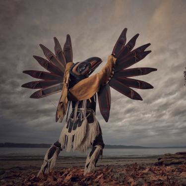 A person wearing a bird mask poses toward the sky.