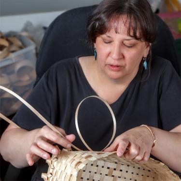 A woman weaving a basket.