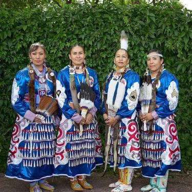 Four women wearing blue patterned dresses.