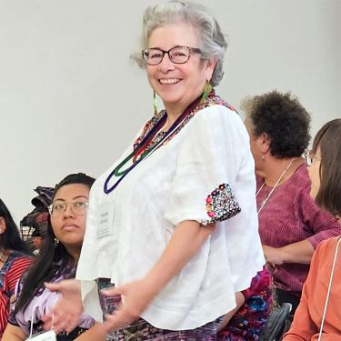A woman wearing glasses and beaded necklaces.