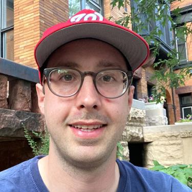 A man wearing a red Washington Nationals ballcap smiles at the camera.