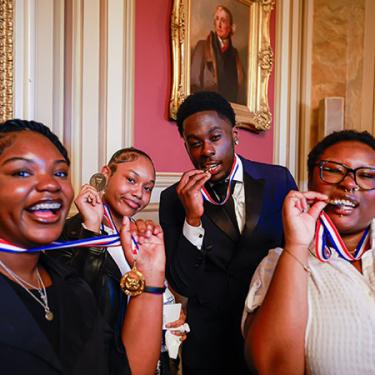 Four young people show off awards on red-white-and-blue ribbons around their becks.