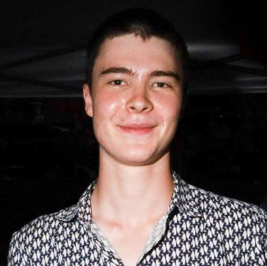 Portrait of a teenage boy with short dark hair and a patterned dress shirt.