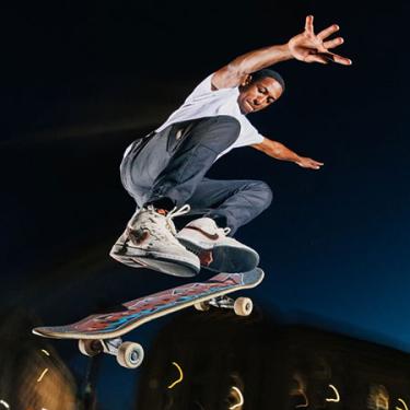 A man does a jump on a skateboard, with arms outstretched mid-air.
