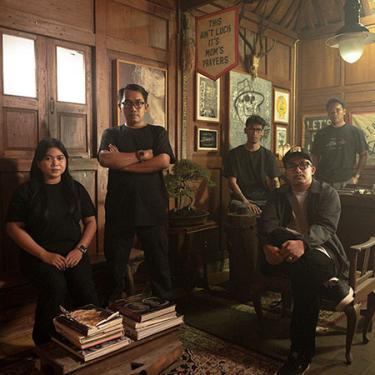 People pose in a wood-paneled room looking tough.