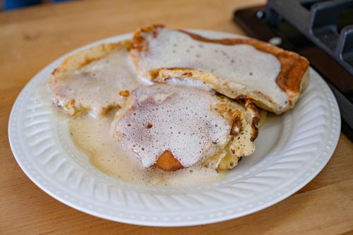 Three sourdough pancakes lathered in melted butter rest on a white plate.