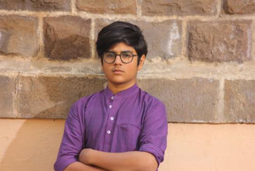A young person poses in a purple dress shirt.