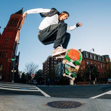 A man does a jump on a skateboard on a city street.