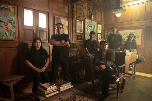 Six people pose in a wood-paneled room looking tough.